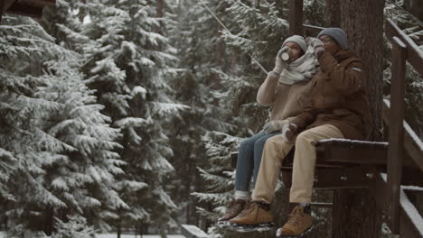 couple enjoying a hot drink in a snowy forest