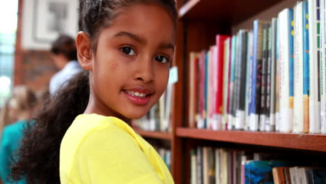 niña sonriendo a la cámara en la biblioteca
