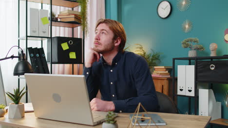 Thoughtful concerned business man working on laptop computer looking away thinking solving problem