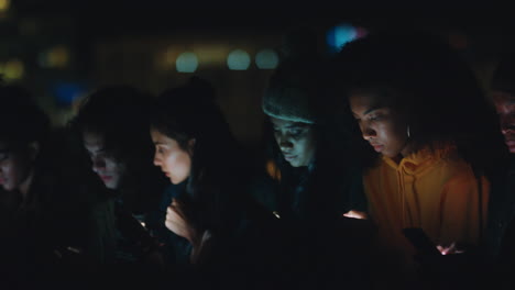 group-of-friends-using-smartphone-mobile-technology-hanging-out-on-rooftop-at-night-enjoying-weekend-sharing-social-media-messages-addiction-concept