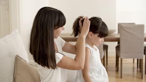 cheerful mom gathering daughters hair in bun