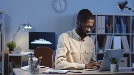 young businessman typewriting on the laptop computer in the office at night