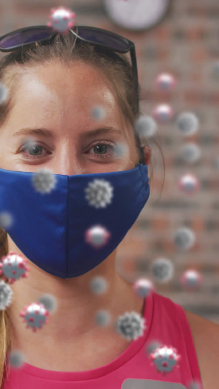 Numerose cellule di COVID-19 che fluttuano sullo sfondo di un ritratto di donna caucasica in forma che indossa una mascherina in palestra.
