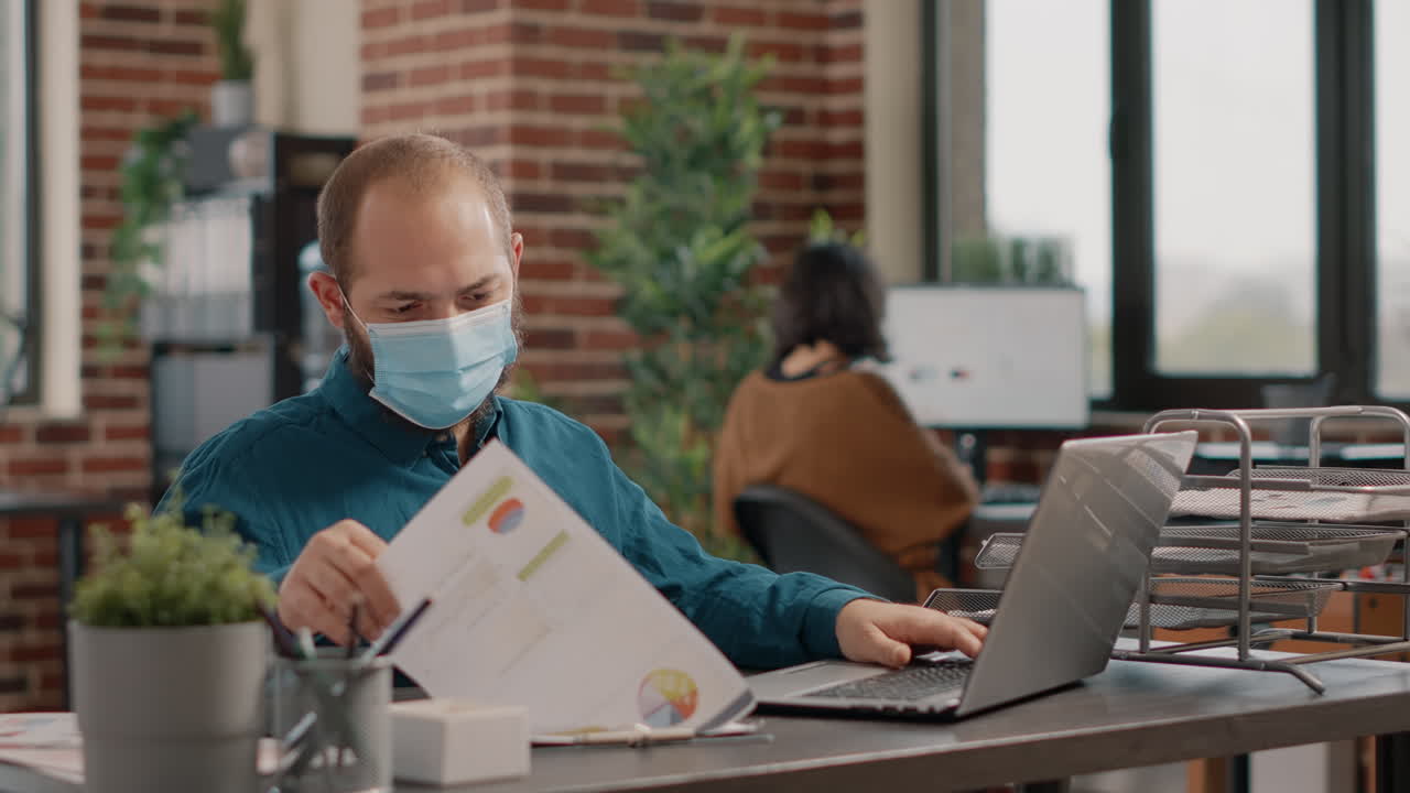 Man working in office with mask on