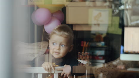 little child with balloon at home view through the window