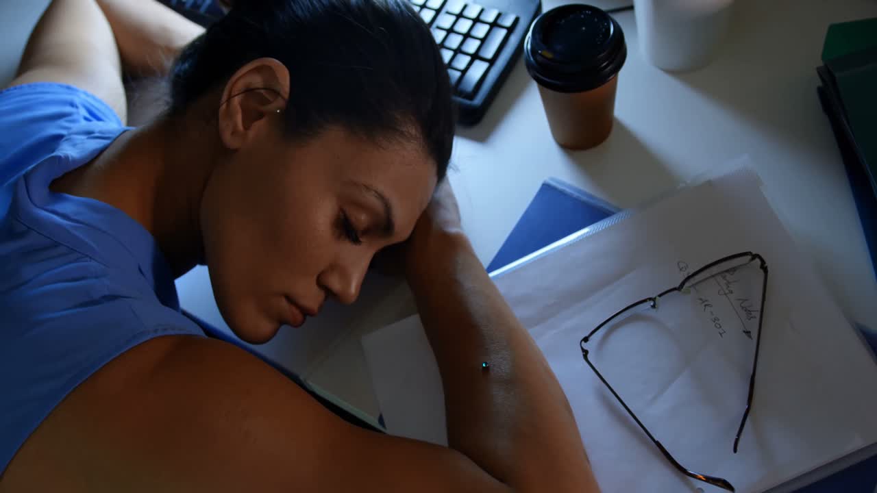 Vista dall'alto di una giovane dirigente caucasica che dorme alla scrivania in un ufficio moderno 4K.