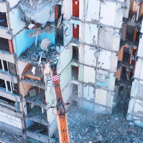 demolishing machine breaks the walls and floors of the big ruined building. aerial view of the deconstruction site