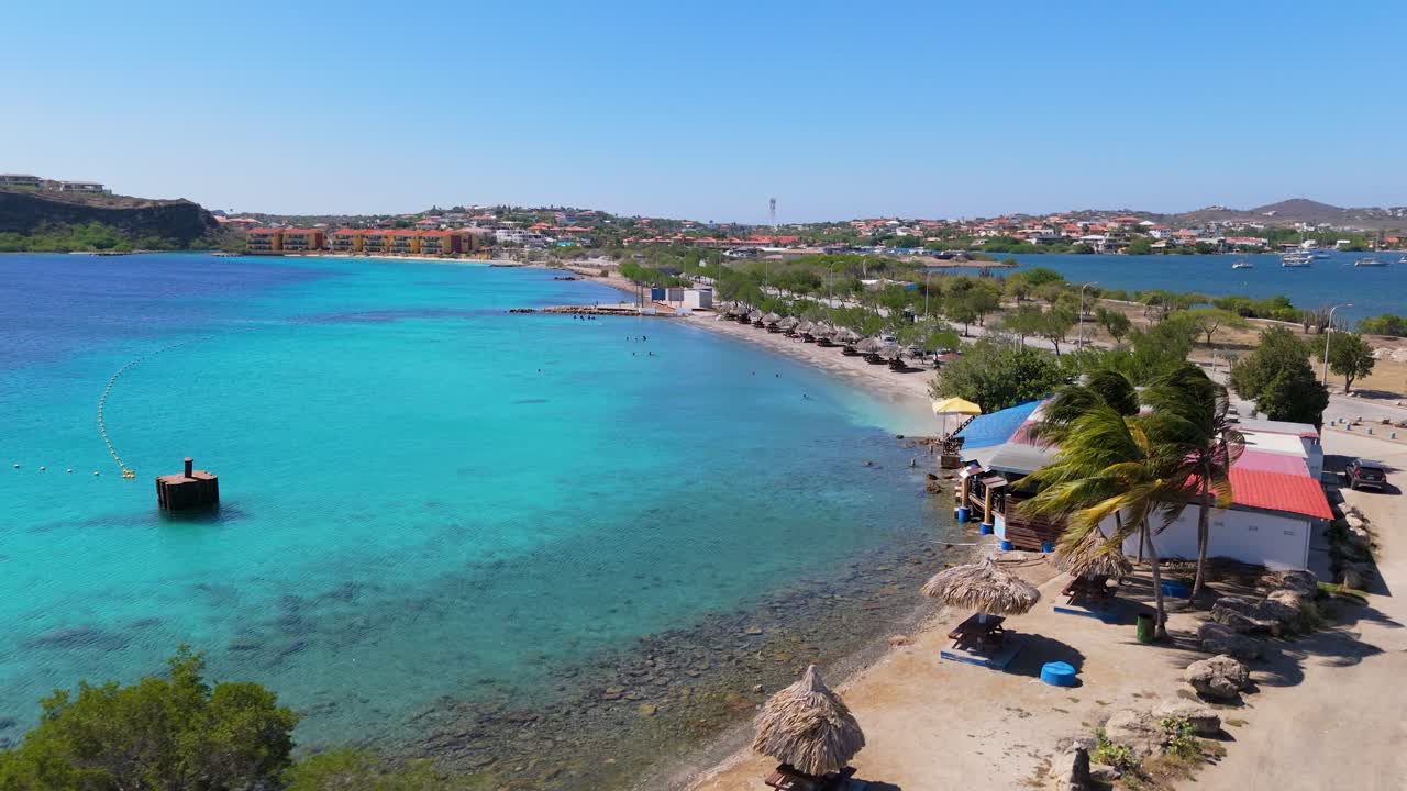 Aerial orbit ascend of Caracasbaai Beach, Curacao, clear blue waters and sandy beaches with coastal vegetation