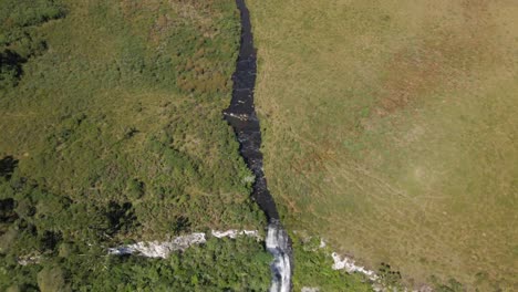 aerial view of river flowing through the rio dos bugres waterfall during summer in urubici, santa catarina, brazil