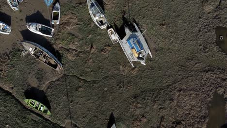 Above-various-stranded-abandoned-fishing-boat-wreck-shipyard-in-marsh-mud-low-tide-coastline-aerial-birdseye-view