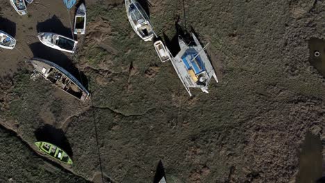 above various stranded abandoned fishing boat wreck shipyard in marsh mud low tide coastline aerial birdseye view