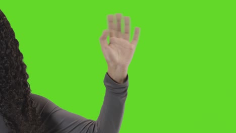 Studio-Close-Up-Shot-Of-Woman-Waving-At-Camera-Against-Green-Screen