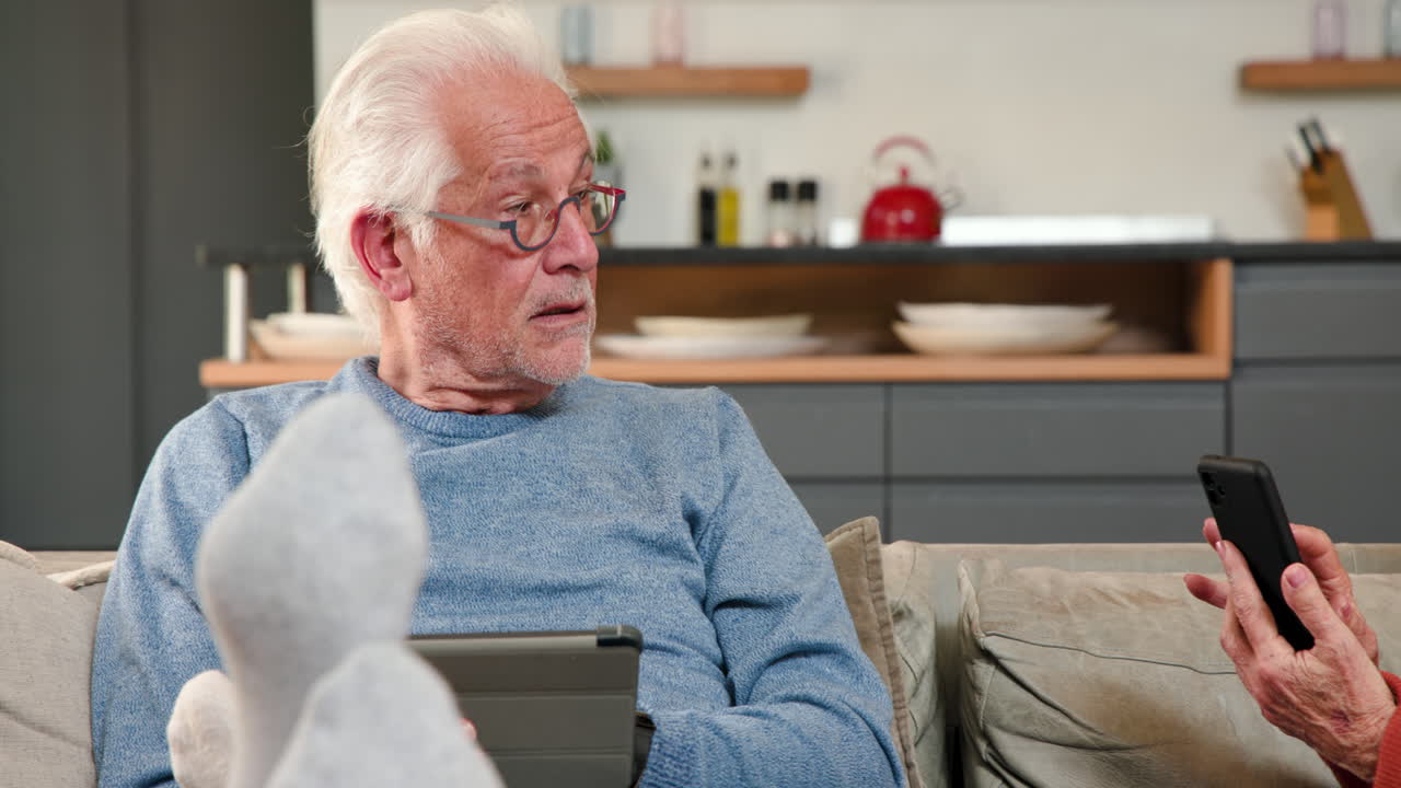 Senior woman enjoying music on headphones while holding smartphone at home