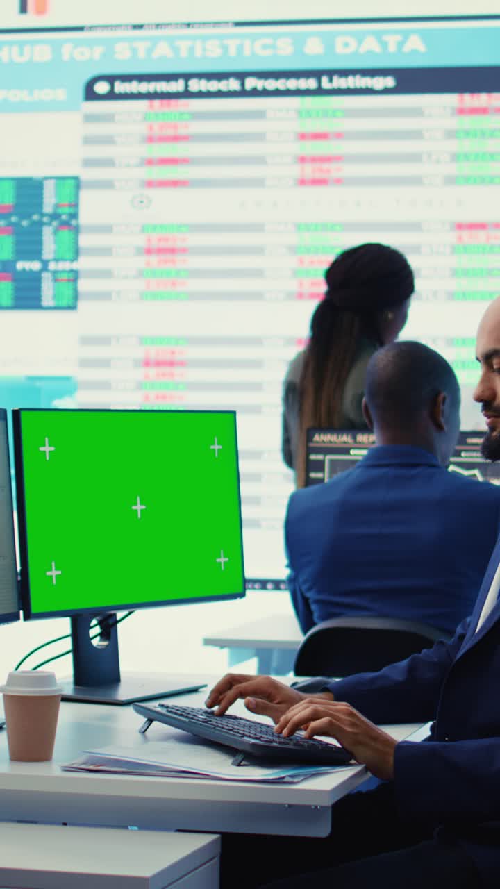 Uomo d'affari che digita sulla tastiera con monitor a schermo verde in ufficio