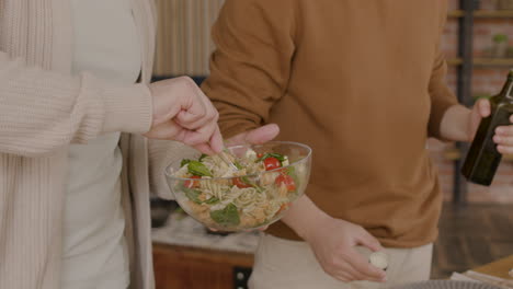 dos hombres aliñando una ensalada antes de una reunión de amigos