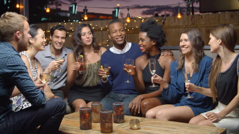 group of friends enjoy night out at rooftop bar, slow motion