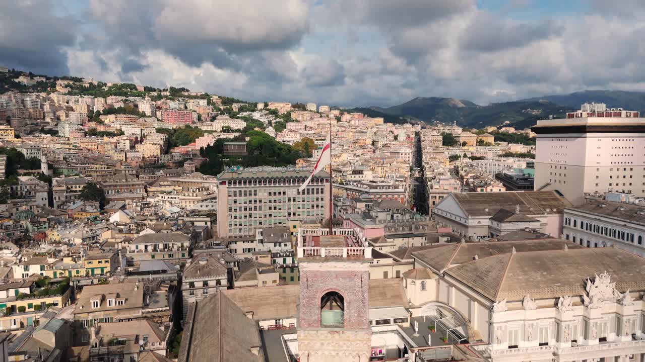 Genoa's historic center with italian flag waving on a sunny day over city rooftops, aerial view