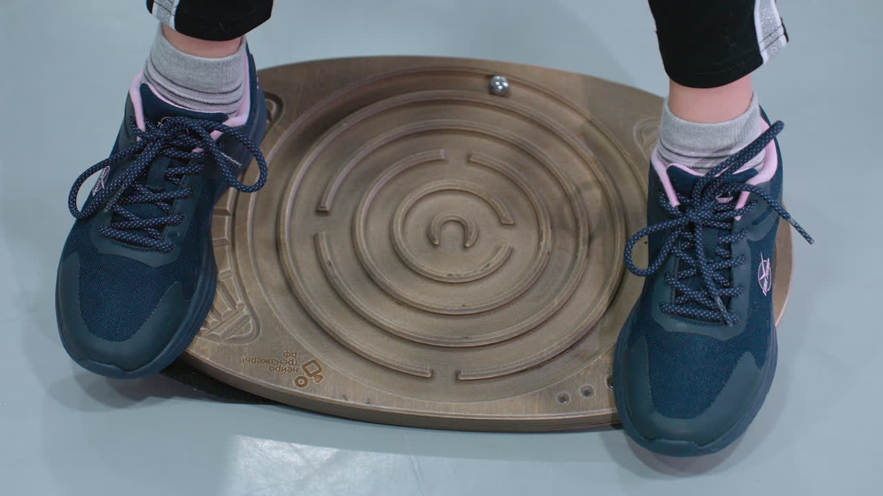 스니커와 조을 입은 사람이 균형 보드에 서서 안정하려고 시도하는 근접 다리 시각.