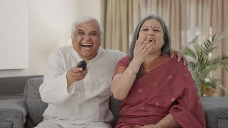 Happy-Old-Indian-couple-watching-TV-and-laughing