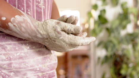 Dirty-hands-of-african-american-female-potter,-standing-in-pottery-studio,-slow-motion