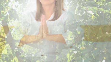 animation of leaves over caucasian woman practicing yoga and meditating