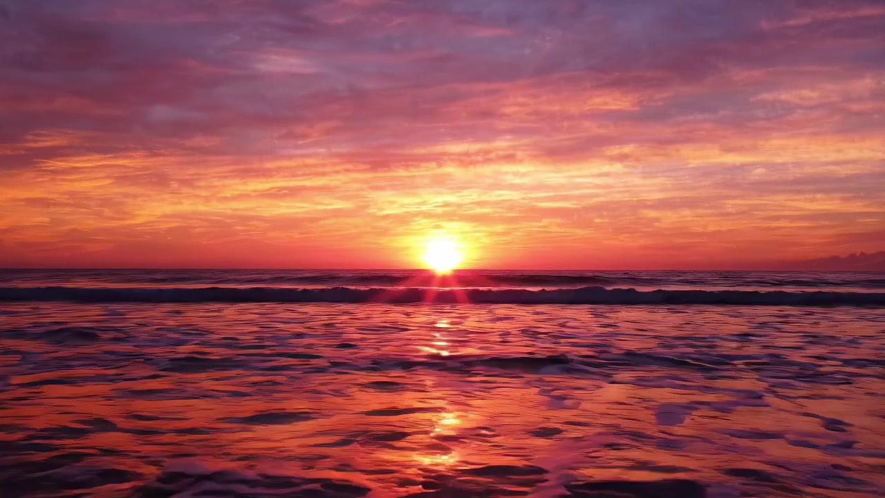 Ein atemberaubender Sonnenuntergang über dem Ozean, wo lebendige Farbtöne von Orange, Pink und Lila nahtlos mit den ruhigen Wellen verschmelzen und eine atemberaubende, friedliche Atmosphäre schaffen.