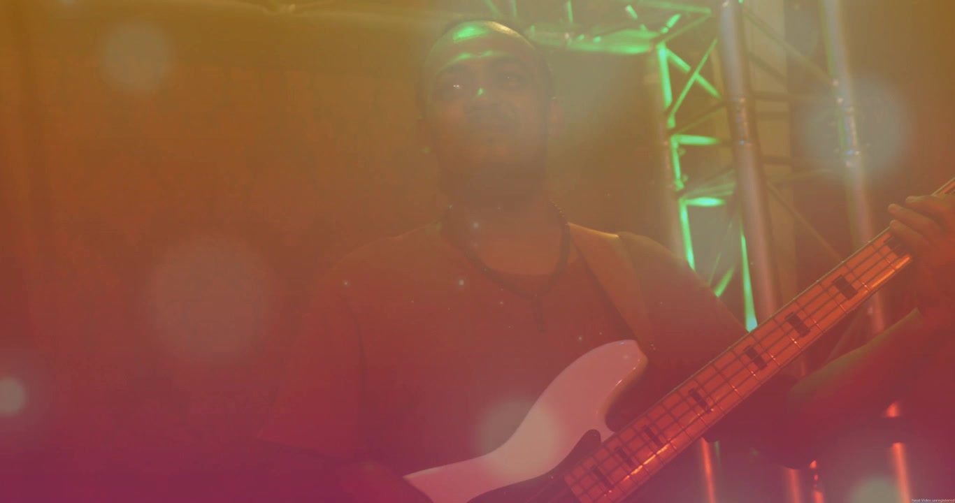 La foschia si dirada e le luci si attenuano, il bassista sposta le mani sul basso bianco mentre si esibisce sul palco.