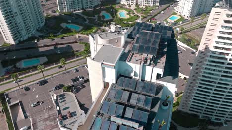 aerial orbit of several solar panels on the rooftop of coastal luxury building