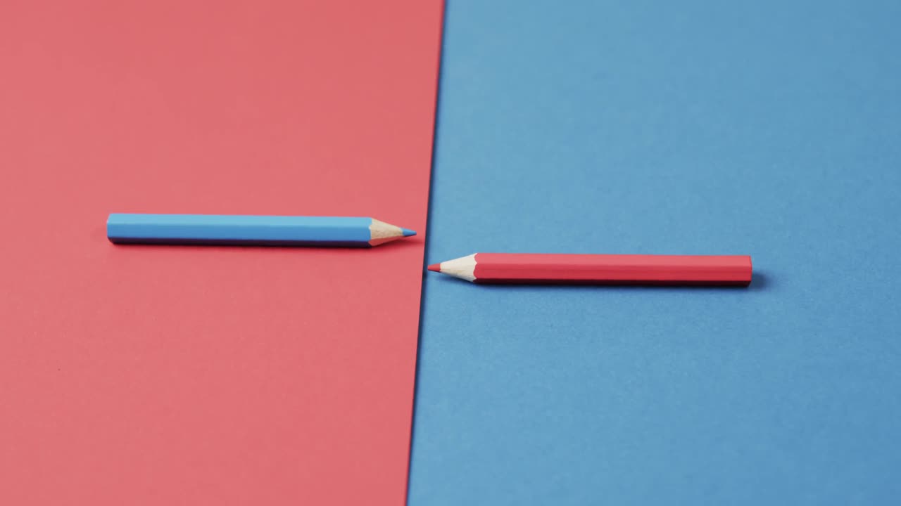 primer plano de lápices de colores azules y rojos dispuestos sobre un fondo rojo y azul, en cámara lenta