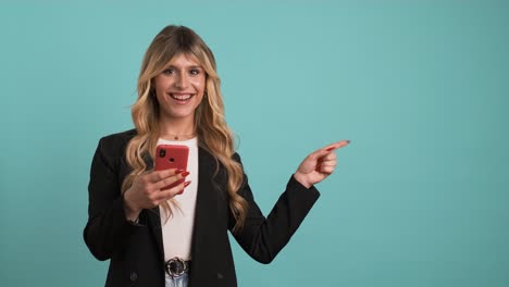 excited transgender businesswoman holding smartphone while gesturing towards blank space