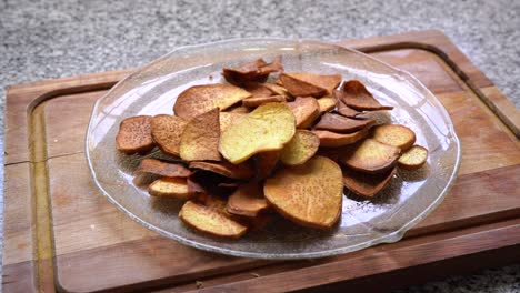 hand picks fried sweet potato chips in a clear glass platter