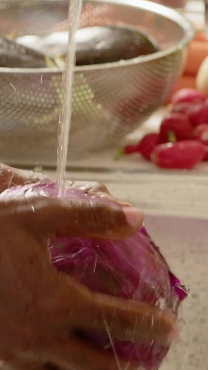 Vertical video: Rinsing hands holding red cabbage under running faucet at home sink, preparing meal