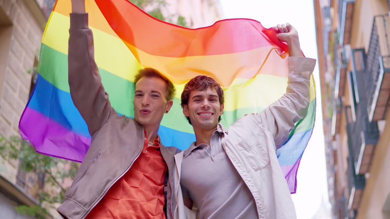 Two Happy Young Men Holding Rainbow Pride Flag in City