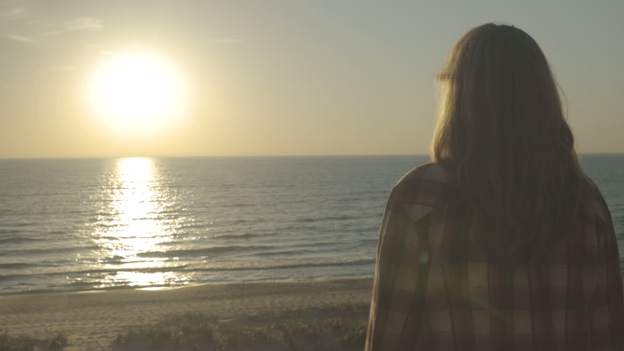 Handheld shot of a woman looking out to the sunset.  Shot in 4K