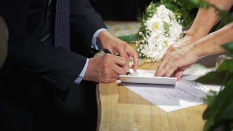 primer plano de la novia y el novio firmando el contrato de matrimonio en la fiesta de la boda