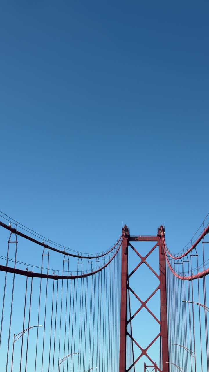 Guida sotto un ponte sospeso rosso con un cielo azzurro e limpido