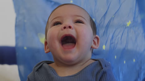 baby smiling and laughing playing with a blue silk with yellow stars in slow motion