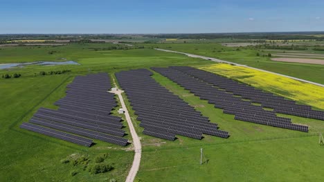 Drohnenaufnahme-Eines-Großen-Solarparks-Auf-Einer-Grünen-Wiese-Außerhalb-Einer-Großen-Europäischen-Stadt