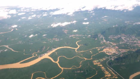 a view of the upper plane window while floating in the air, overlooking the mountains and natural water resources along the coast of thailand