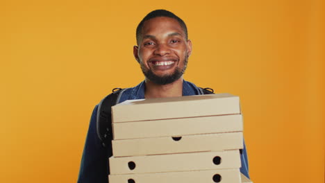 African-american-pizzeria-deliveryman-holding-stack-of-pizza-boxes