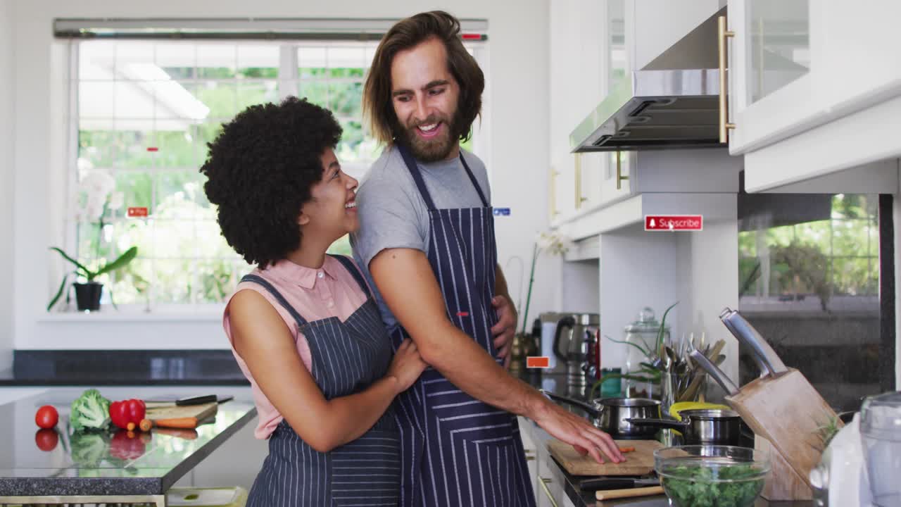 Man washing veggies and stirring ingredients with woman hugging him, causing social media icons