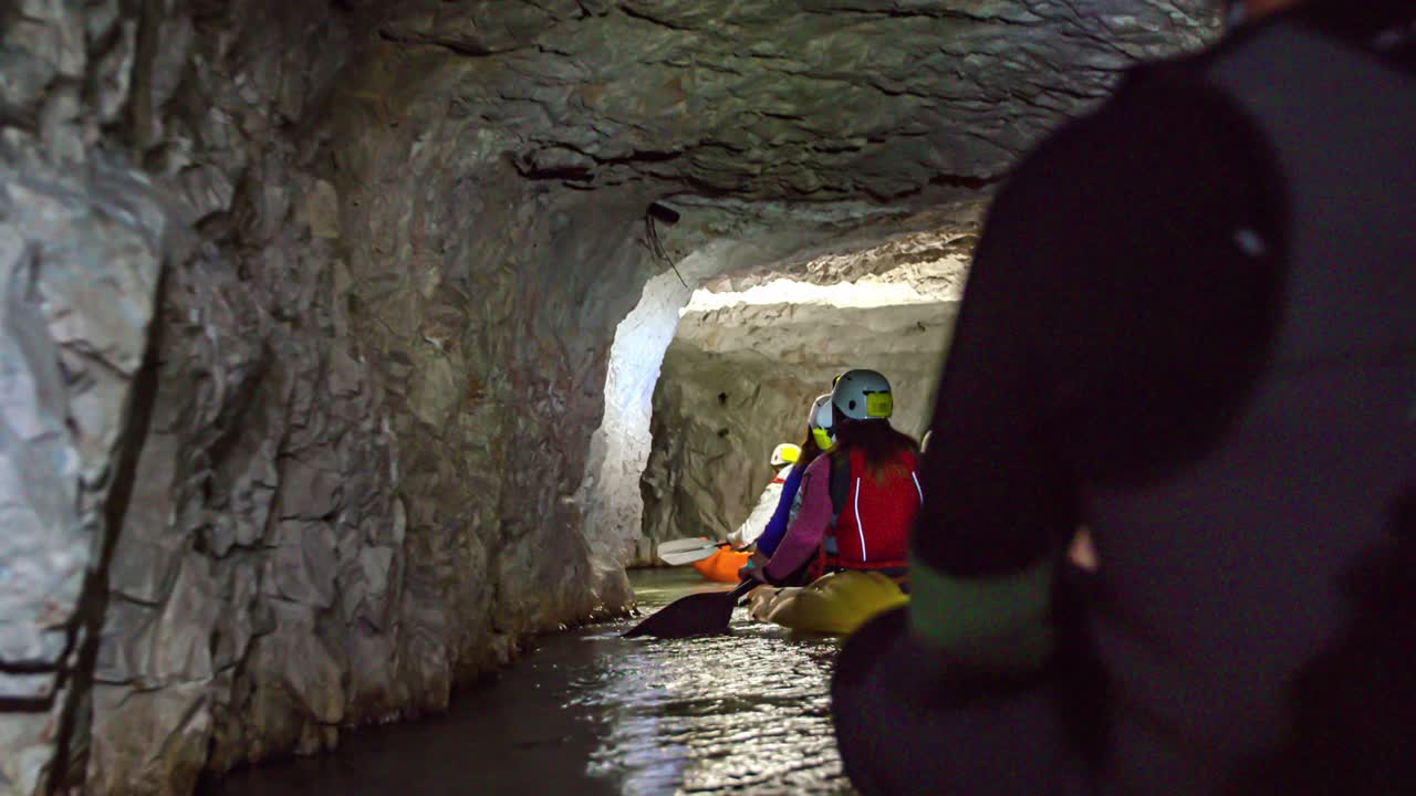 Travelers enjoying the thrilling experience of underground kayaking at mining museum in Glančnik in Mežica. View from back