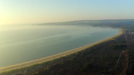 una amplia toma aérea de la bahía de studland en la costa de dorset con vistas a los acantilados de old harry rock y un hermoso amanecer y aguas tranquilas del mar