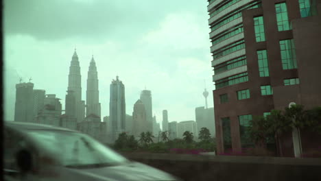 Paisaje-Urbano-De-Kuala-Lumpur-Revelado-Como-Se-Ve-Desde-El-Interior-Del-Metro,-Lluvioso-Afuera,-Gotas-De-Lluvia-En-La-Ventana-Exterior-Del-Viajero