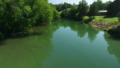 aerial flyover of mirror-like creek, lush forest scenery