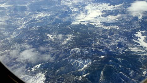 snowed mountains over northern california during winter, aerial airplane window shot