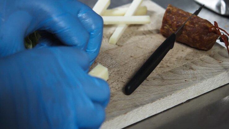 Primo piano al rallentatore di uno chef con i guanti che sistema il formaggio su un piatto.