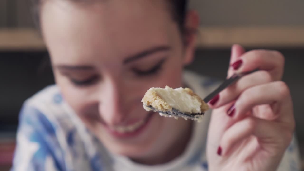 hermosa chica está mostrando un trozo de pastel sabroso con un tenedor