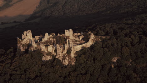 Toma-Aérea-De-Las-Ruinas-Del-Castillo-De-Gymes-Iluminadas-Por-Los-últimos-Rayos-Del-Atardecer