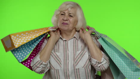 Abuela-Mayor-Levantando-Bolsas-De-Compras,-Celebrando,-Satisfecha-Con-La-Compra,-Descuento.-Clave-De-Croma